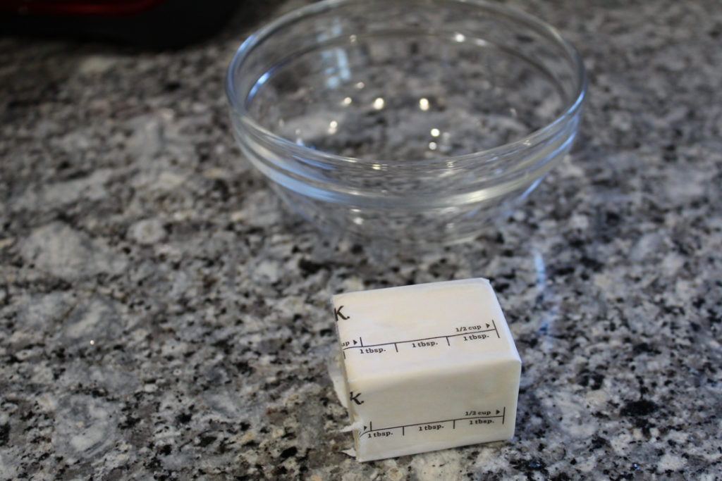 3 tbsp of butter on the counter sitting in front of a small glass bowl. 